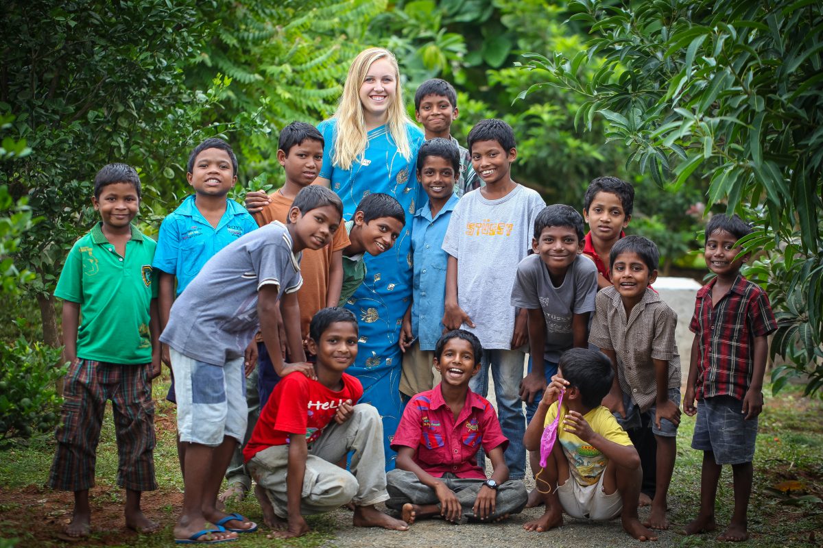 A volunteer from the United States poses with a group of boys from Children of Faith Home in India