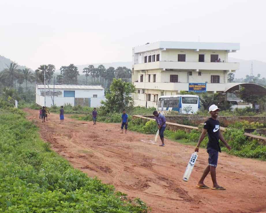 Boys are playing cricket in front of a Children Faith dormitory