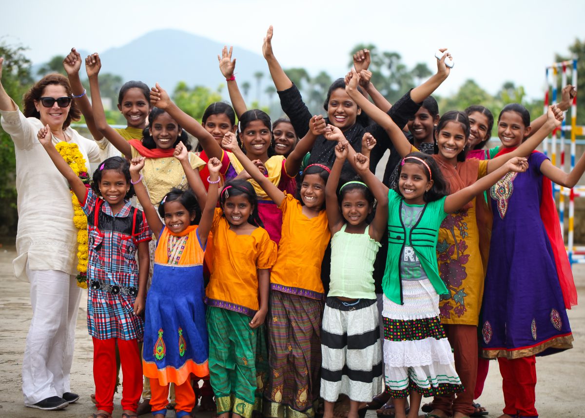 a group of young girls from Children of Faith with hands in the air with Rose and a visitor