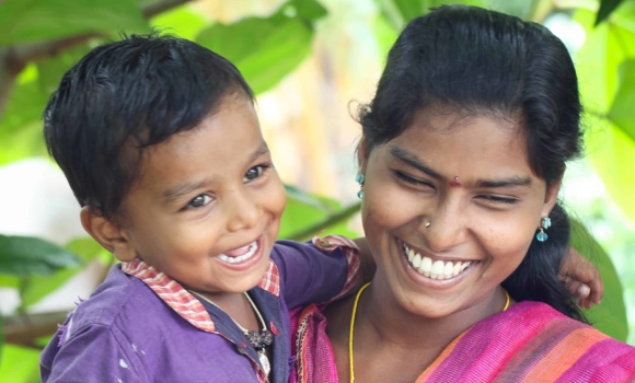 a young woman holding a young smiling boy on her hip