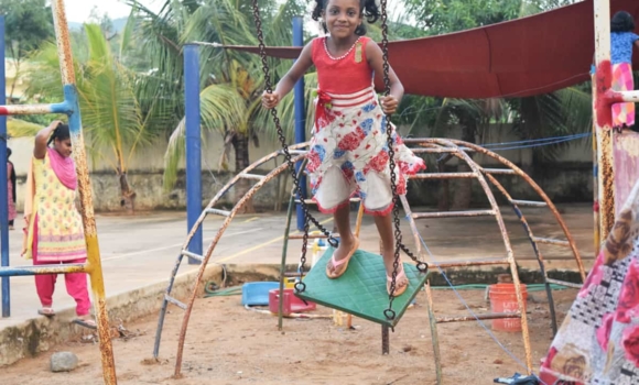 young girl standon on swin in Children of Faiths playground