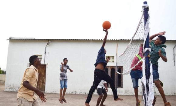 young men at children of faith play yard playing volleyball