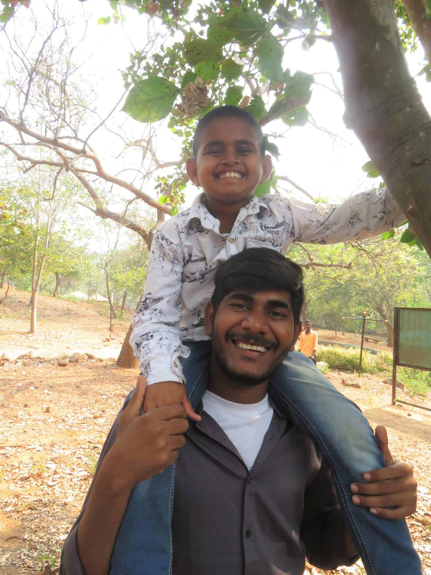 A young boy on the shoulders of a man outside in India