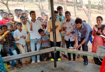 Children gather around their teacher to celebrate his birthday