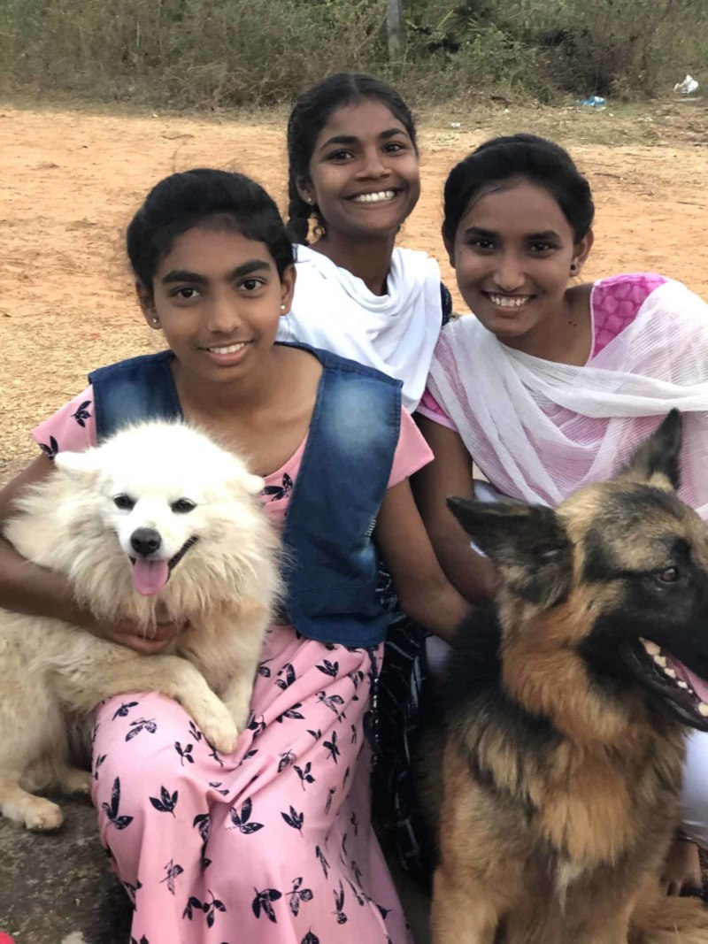 Three Indian girls hold two dogs