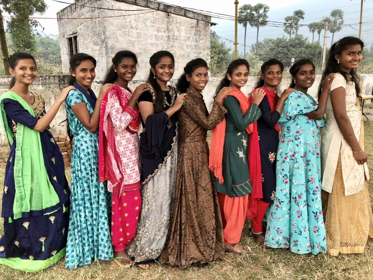 Girls in a line smiling at the camera in India