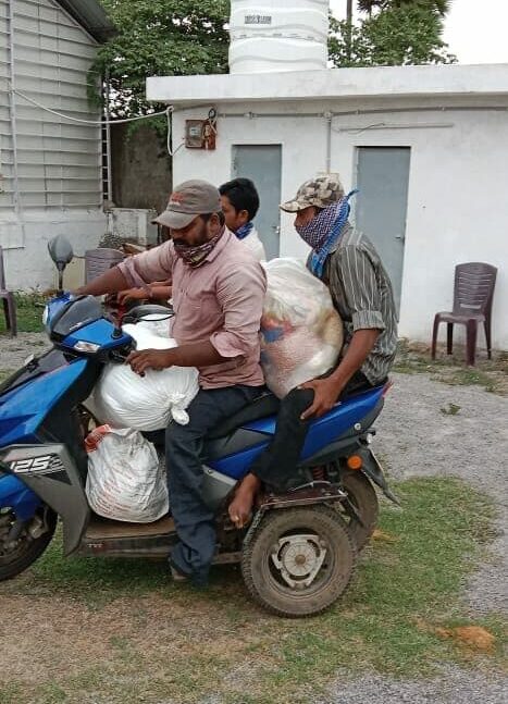 Men on a motor bike transport supplies from Grocery distribution event in India