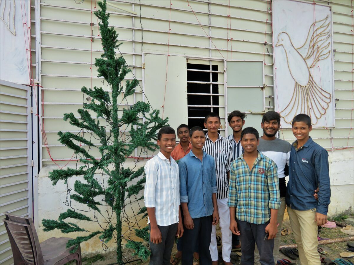 Boys gather beside a Christmas tree decorating a church in India