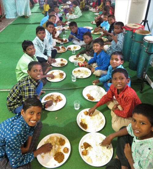A long line of boys enjoying Christmas lunch in India