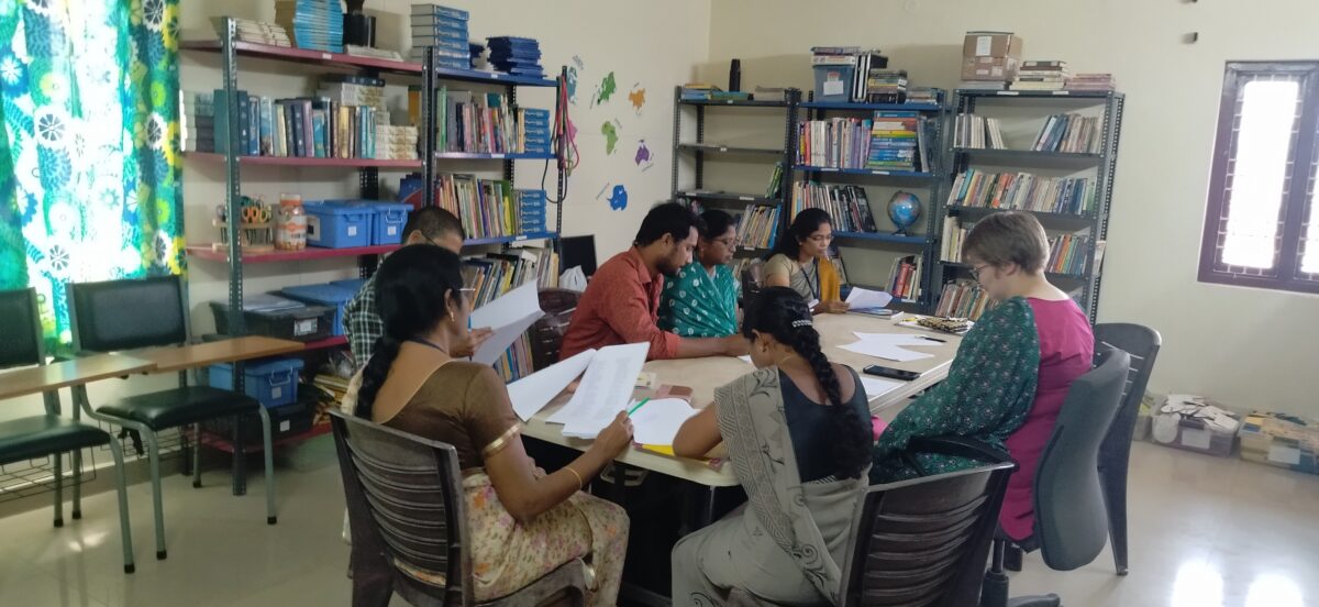 Teachers gather around a table to learn to use the school's library in Inida
