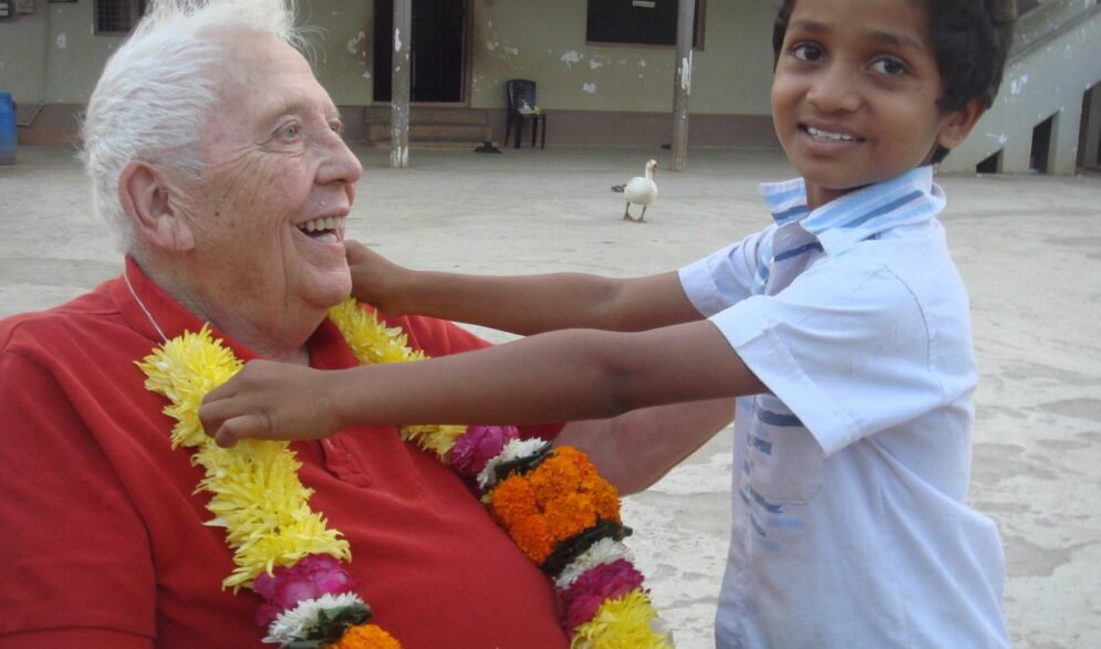 A supporter visiting India from the from the US smiles at a small boy