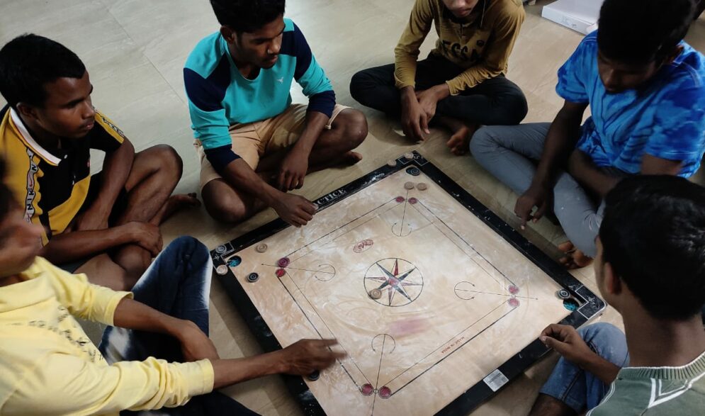 Children gather around a game board at the Children of Faith Home in India