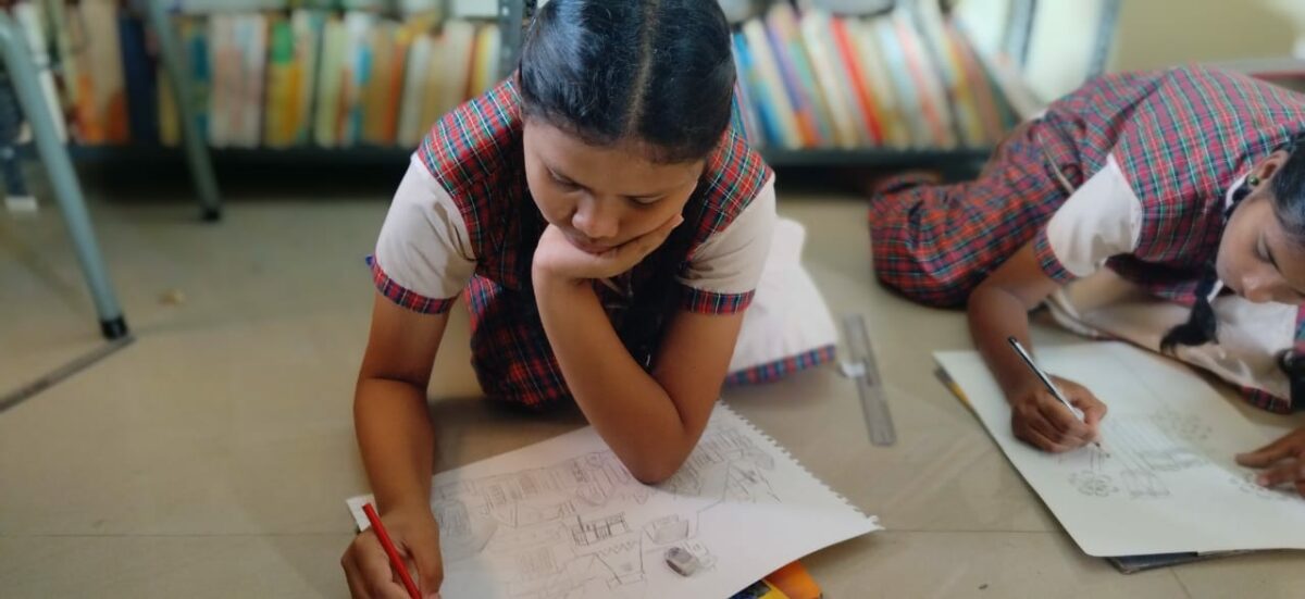 A young girl in India writes a note in  a beautiful handmade card as a thank you to her sponsor in the Children of Faith Home in India.