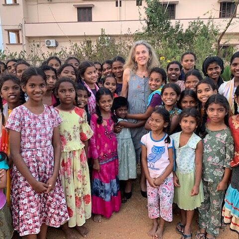 A visitor to the Children of Faith Home in India stands with several young women and girls