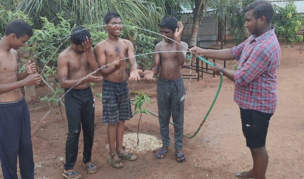 Boys cool off in the hose at Children of faith in India