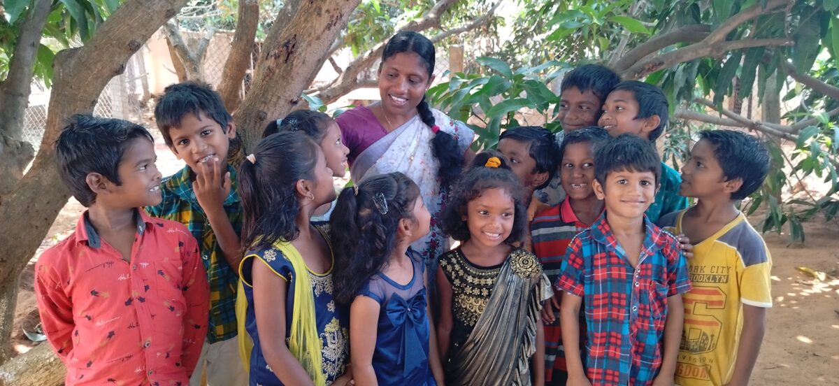 children with a teacher at the Children of Faith Home in India