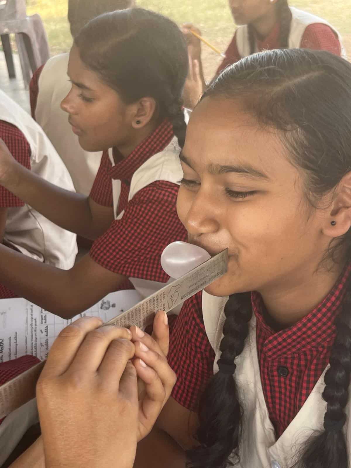 Girls blowing bubbles with gum at Children of Faith in India