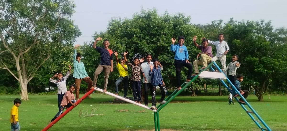 Boys from children of Faith pose and wave on a climbing structure at the park