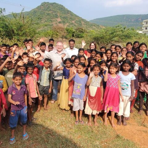 Visitors wave with children at Children of Faith Home in India