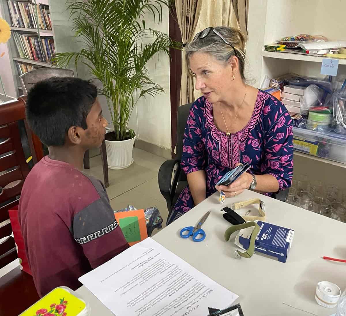 A visitor to children of Faith works in the classroom with the children